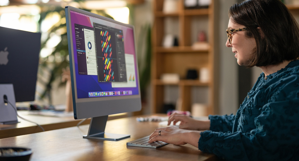 一個人在辦公室環境使用 iMac，螢幕顯示色彩繽紛的設計 app