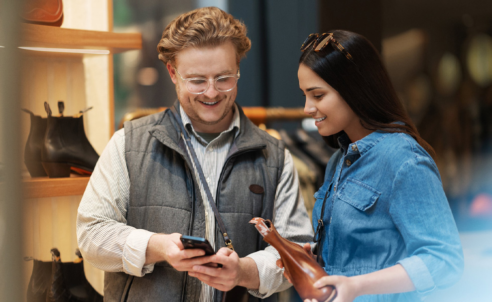 Een verkoopmedewerker gebruikt een iPhone in de winkel om een klant te helpen.