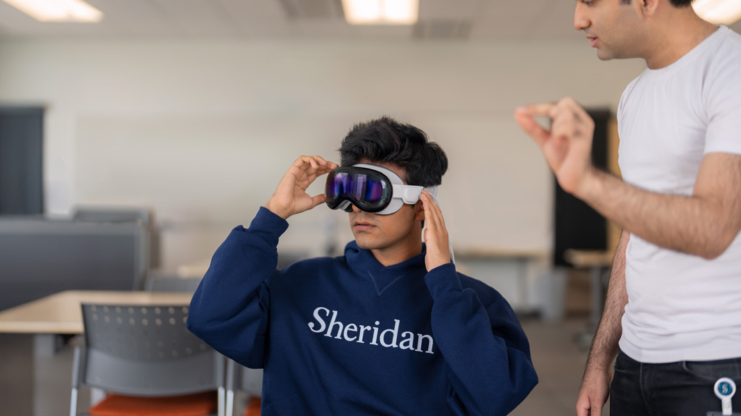 Um estudante vestindo uma camiseta da Sheridan College experimenta óculos de realidade mista