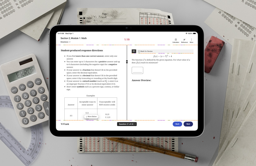 En iPad ligger på ett skrivbord tillsammans med fysiska provformulär och skolmaterial. På skärmen finns anvisningar om hur man gör mattedelen av ett standardiserat prov.
