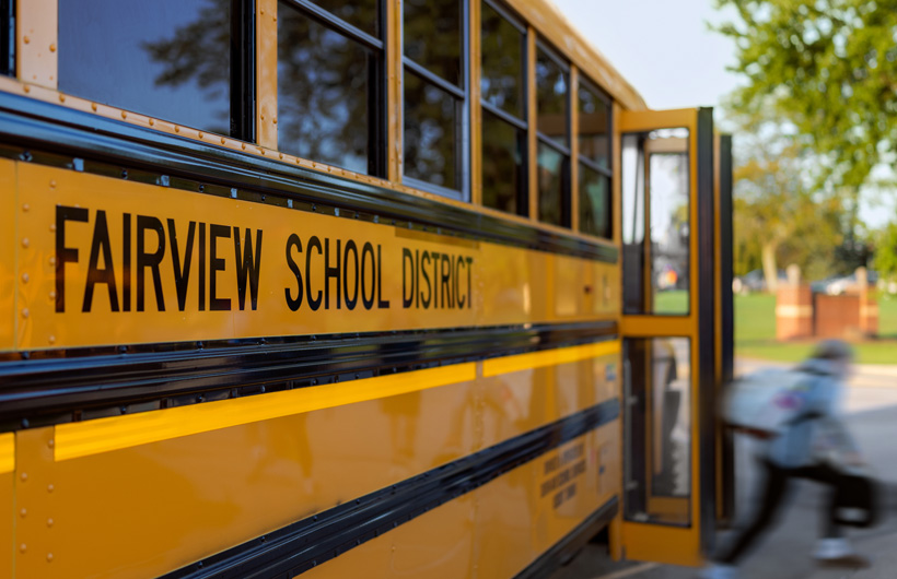 En närbild från sidan som visar hur ett barn kliver av en skolbuss från Fairview School District.
